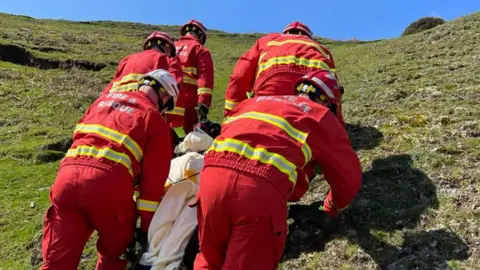 Shropshire Fire and Rescue Service Firefighters climbing a hill with a patient