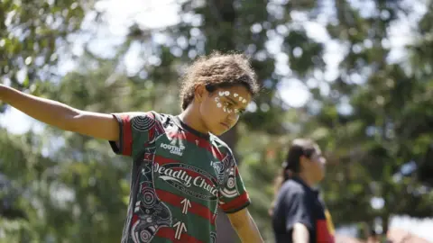 Getty Images A kid performs a traditional dance at Musgrave Park during the rally. Indigenous Yuggera and Turrbal people organised a rally known as Meanjin on a date synonymous with the beginning of British colonial rule and oppression of Aboriginal people.