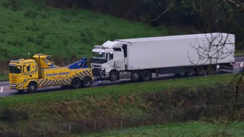 A recovery lorry tows the lorry that was involved in the crash away from the scene