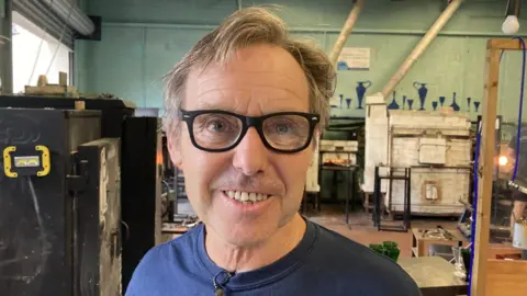 A man with glasses on smiling at the camera