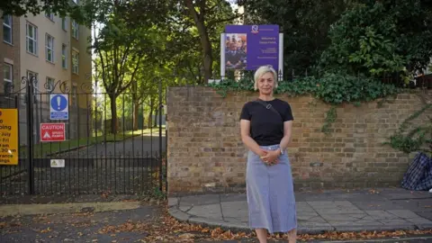 PA Media Miranda Sawyer stands outside the gates to St Martin in Tulse Hill, Lambeth.