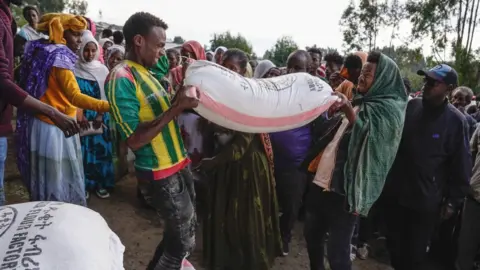 Getty Images Volunteers lift bags of food aid at a displaced people's camp in Debark in Amhara, Ethiopia - October 2021