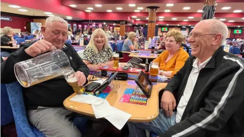 Couples Andrew and Carol Mortimer and Andrew and Marie Marsters enjoy a drink and game of bingo