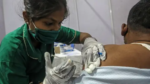 EPA A man receives a shot of COVID-19 vaccine inside a vaccination centre in Mumbai, India, 12 April 2021.