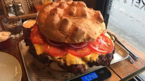 A giant burger weighing over 5kg being weighed on scales