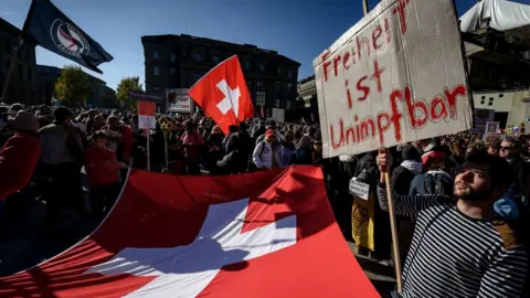Getty Images A protester holds up a banner reading in German 'freedom is unvaccinable' during a rally in opposition with the current measures to tackle the spread of the coronavirus, Covid-19 health pass and vaccination, in Bern on October 23, 2021