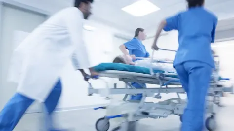 Getty/SCIENCE PHOTO LIBRARY Hospital emergency, medical staff pushing patient on gurney.