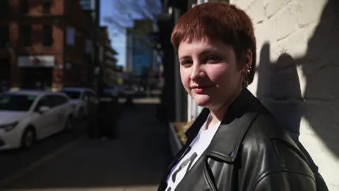 BBC/Dan Nelson Young person leans against a wall and looks at the camera