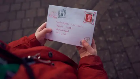 Gareth Cattermole Child hands hold a letter addressed to Father Christmas