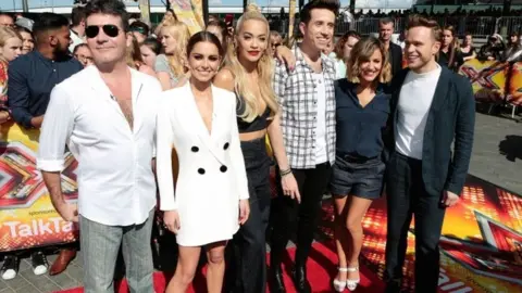 PA Media (l-r) Simon Cowell, Cheryl Fernandez-Versini, Rita Ora, Nick Grimshaw, Caroline Flack and Olly Murs