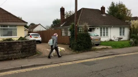 BBC Wales Sian Healey walking down the street with her guide dog Uri