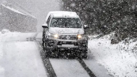 PA Media Pick up truck drives in heavy snow