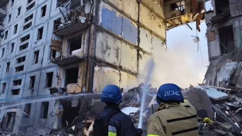 MARYNA MOISEYENKO Rescuers try to extinguish a fire in a residential building damaged after a Russian missile strike in the city of Zaporizhzhia on 9 October 2022