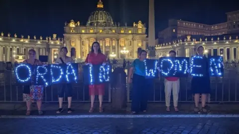 Women's Ordination Conference Women hold a sign saying Ordain Women