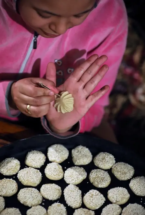 Reuters A woman uses a pin-like implement to make decorative pattern on a small pastry before it goes in an oven.