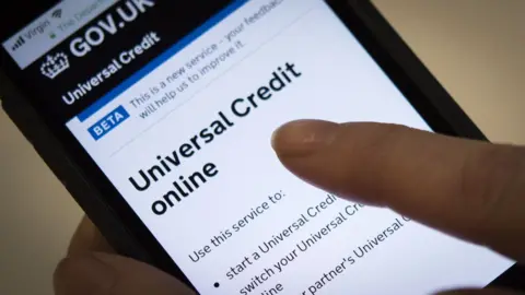 BBC hand holding phone applying for universal credit online