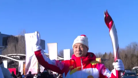 A torchbearer with the Winter Olympics flame