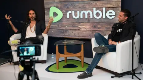 Rumble Russell Brand, left, at a Rumble event