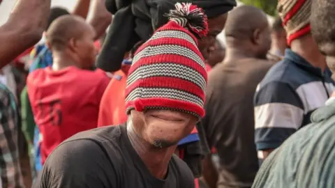 BBC Man with a read woollen hat pulled over his eyes in Arondizuogu during the Ikeji Festival in Nigeria