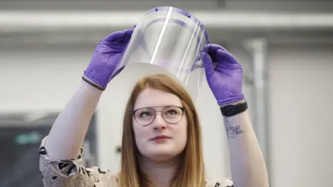 PA Media Louise France, Director of Medical Engineering at the University of Hull, inspects a 3D-printer faceguard produced to help health service staff tackle coronavirus.