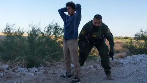 Getty Images Migrant and Border Patrol officer