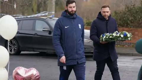 PA Media Birmingham City Football Club head coach John Eustace (right) laying flowers near to the scene