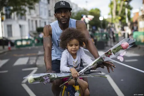 Getty Images A nearby resident and his daughter bring flowers on a bike