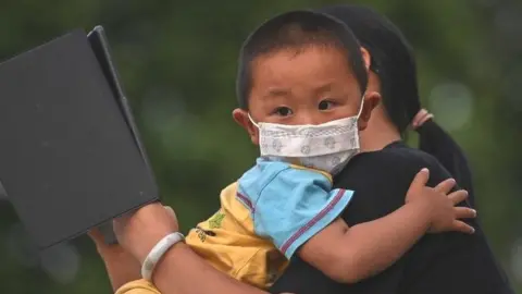 Getty Images A mother holds his son next to Yangtze River in Wuhan, in Chinas central Hubei province on May 12, 2020. -