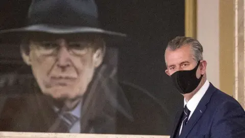 PA/Liam McBurney Edwin Poots near a portrait of Ian Paisley at Stormont