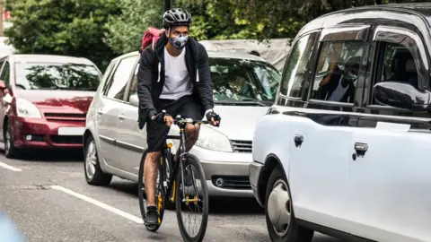 Getty Images Cyclist riding on street with traffic jam