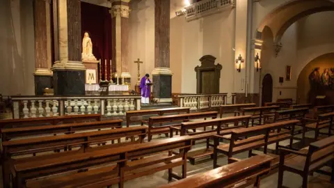 Getty Images Priest Carlos Enrique Leal offers Mass via YouTube to parishioners at an empty Santa Maria de Betlem church on March 15, 2020 in Barcelona, Spain
