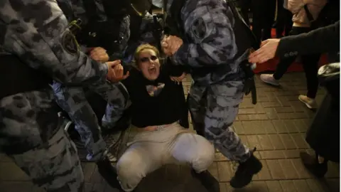 Getty Images A woman is detained by police officers