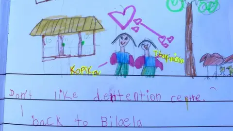 HOMETOBILO  One of Kopika's drawings show two girls standing in front of detention housing. She has written: "Don't like detention centre. I back to Biloela"