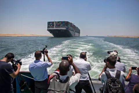 Mahmoud Khaled / AFP Journalists on a nearby boat film the Ever Given container ship on the Suez Canal, Egypt, on 7 July 2021