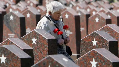 AFP A woman walks past graves of soldiers killed during WW2 at a cemetery in central Moscow (8 May 2006)