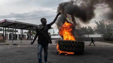 EPA A man with a burning tyre in the background