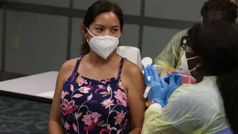 Getty Images Woman being jabbed at Miami-Dade vaccine centre