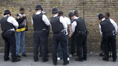 Getty Images Police search a group of people