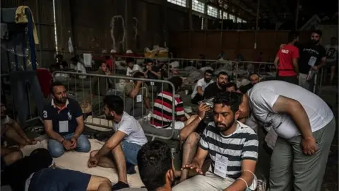 Getty Images Survivors sit inside a warehouse in Kalamata, Greece on 15 June, 2023