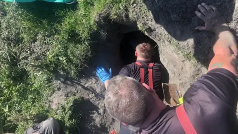 Cambridgeshire Fire & Rescue Service Firefighters getting to a dog down a hole