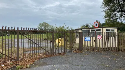 Guy Campbell/BBC A metal gate and empty brownfield site