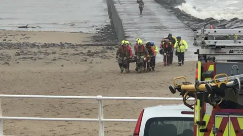 @Beachdog_Wales The fisherman was stretchered off the pier by emergency services after falling into the sea.