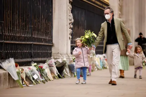 AFP A child carries a floral tribute to Britain's Prince Philip, Duke of Edinburgh outside Buckingham Palace, central London on 10 April 2021