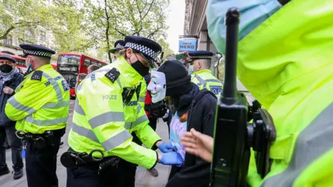 Getty Images A police officer searches a pro-Palestinian demonstrator outside Elbit System HQ in London during a protest against Israeli air raids on the Gaza Strip, on May 11, 2021