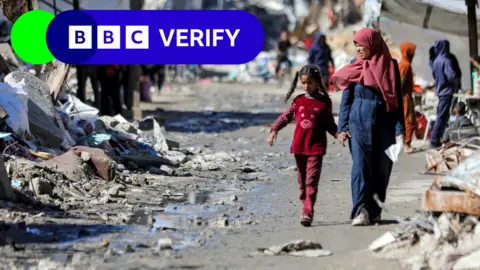 Woman and child walk through rubble in Gaza