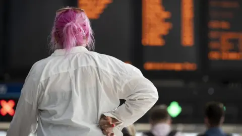 Getty Images Woman looks at rail departures board