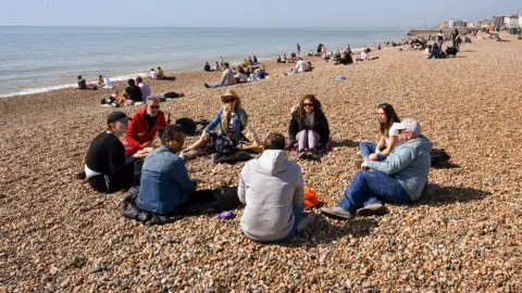 Getty Images People enjoy the warm weather on Brighton beach