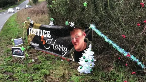 A Christmas tree and decorations surround a banner for Harry Dunn outside RAF Croughton