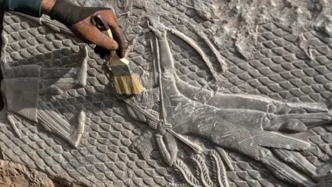 Getty Images An Iraqi worker excavates a rock-carving relief found at the Mashki Gate, from the ancient Assyrian city of Nineveh, on the outskirts of today's Mosul, 19 Oct 22