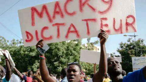 AFP A demonstrator holds a placard reading "Macky dictator" during a rally to demand the release of detained Senegalese opposition leader Ousmane Sonko.